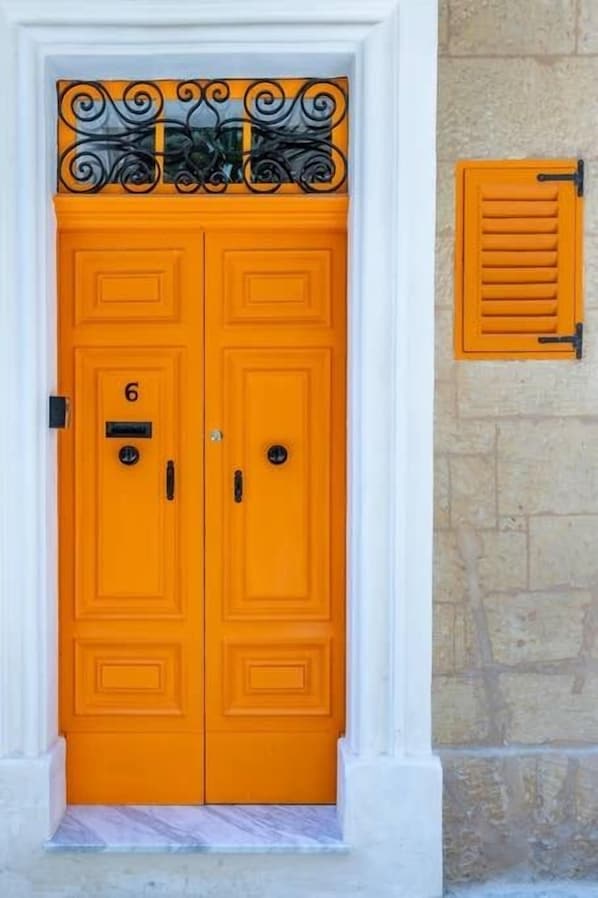 A double door with a number '6' and a small plaque, set in a white frame with a decorative black metal top.