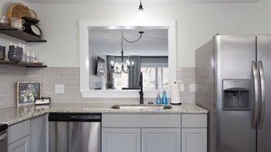 A modern kitchen with a stainless steel refrigerator, a dishwasher, and a sink with a window above it. - *NEW* Cozy, Smart Condo| 10 mins to DT, Biltmore (Asheville)