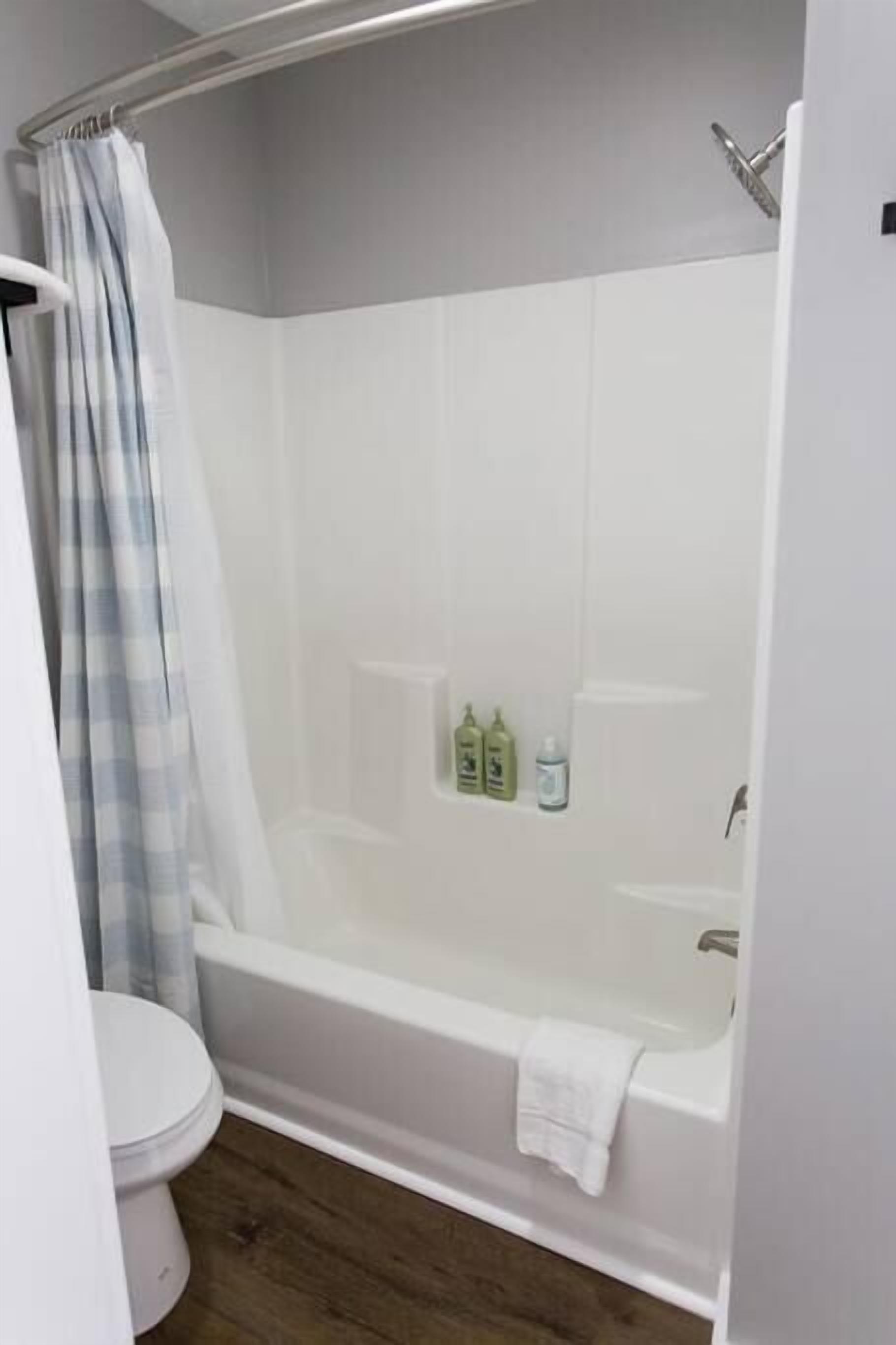 Un baño con bañera, inodoro y cortina de ducha.