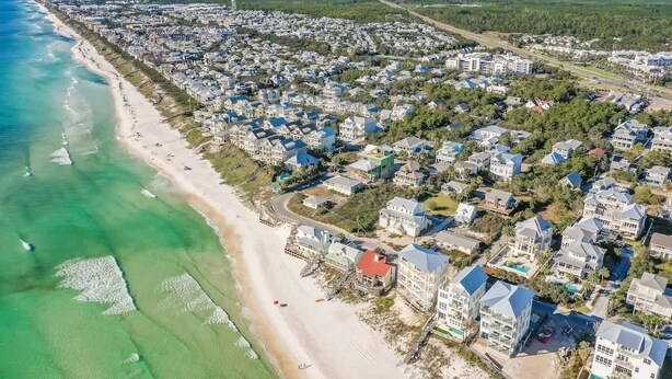 Vista aérea de una zona residencial costera con casas a lo largo de la playa y una vista despejada del océano.