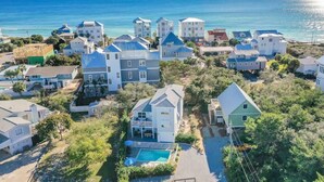 Vista aérea de una zona residencial costera con casas, una piscina y una vista despejada del océano.