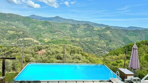 Ein Swimmingpool mit Blick auf grüne Hügel und Berge im Hintergrund.