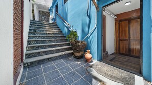Un escalier menant à une porte en bois, avec une plante en pot et un vase placés sur les marches.