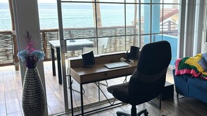 Une chambre avec un bureau, une chaise et une vue sur l’océan.