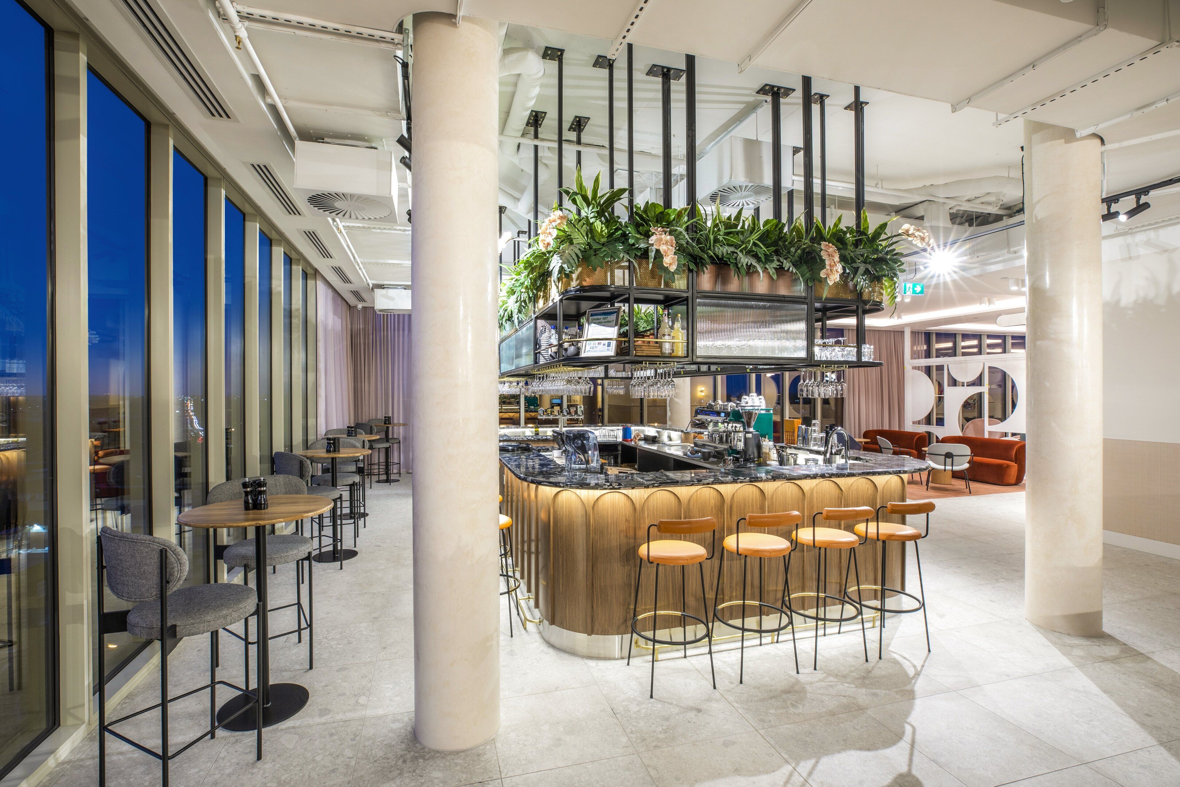 Un espace bar moderne doté d’un îlot central, de tabourets de bar et d’une variété de plantes.