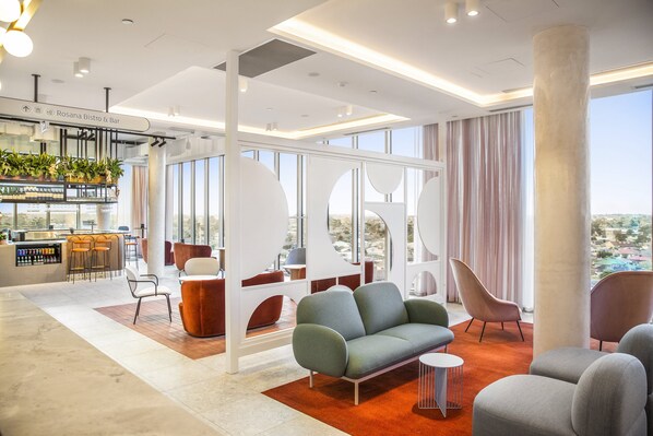 A modern hotel lobby with seating areas, a bar, and large windows offering views. - Holiday Inn Werribee by IHG (Werribee)