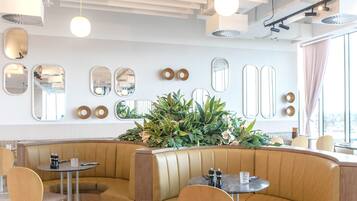 Un restaurante moderno con asientos tipo cabina, mesas redondas y un gran centro de mesa con plantas.