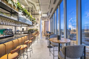 A modern bar area with high stools, a counter with glassware, and a view of the city through large windows. - Holiday Inn Werribee by IHG (Werribee)