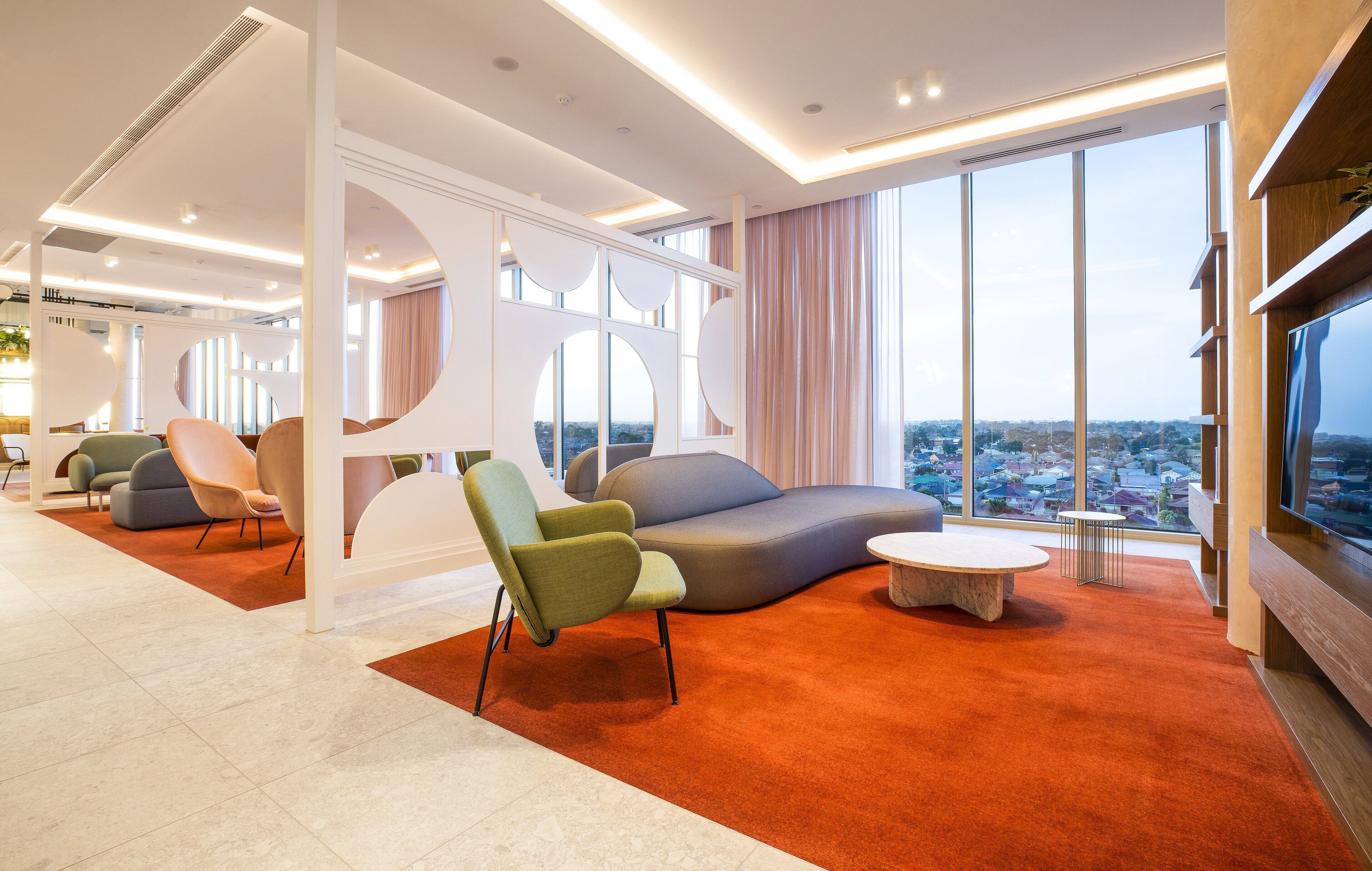 A modern hotel lobby with a large seating area, a view of the city, and a large window.