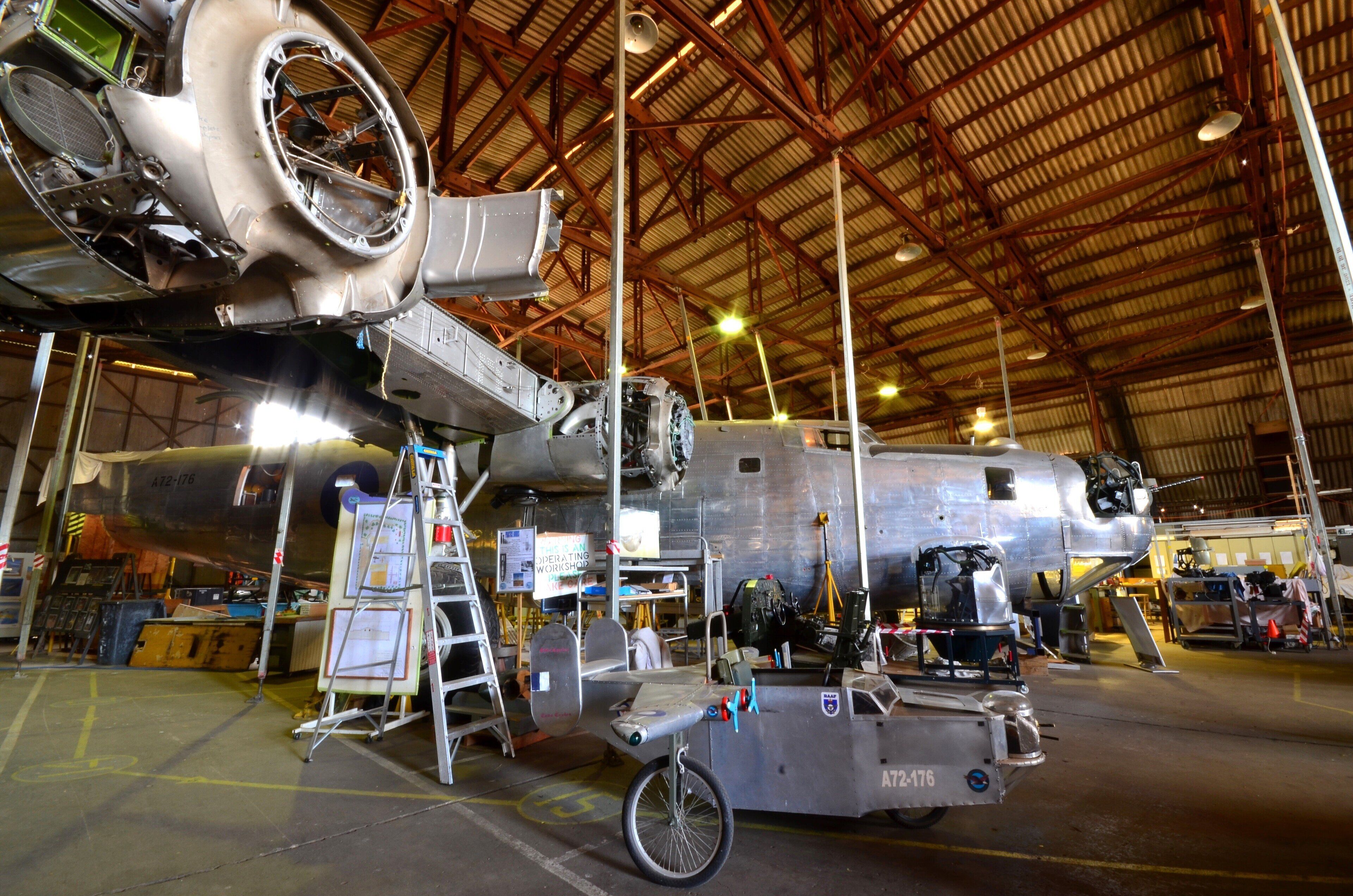 Et stort fly med metaloverflade, en stige og et arbejdsbord i en indendørs hangar.
