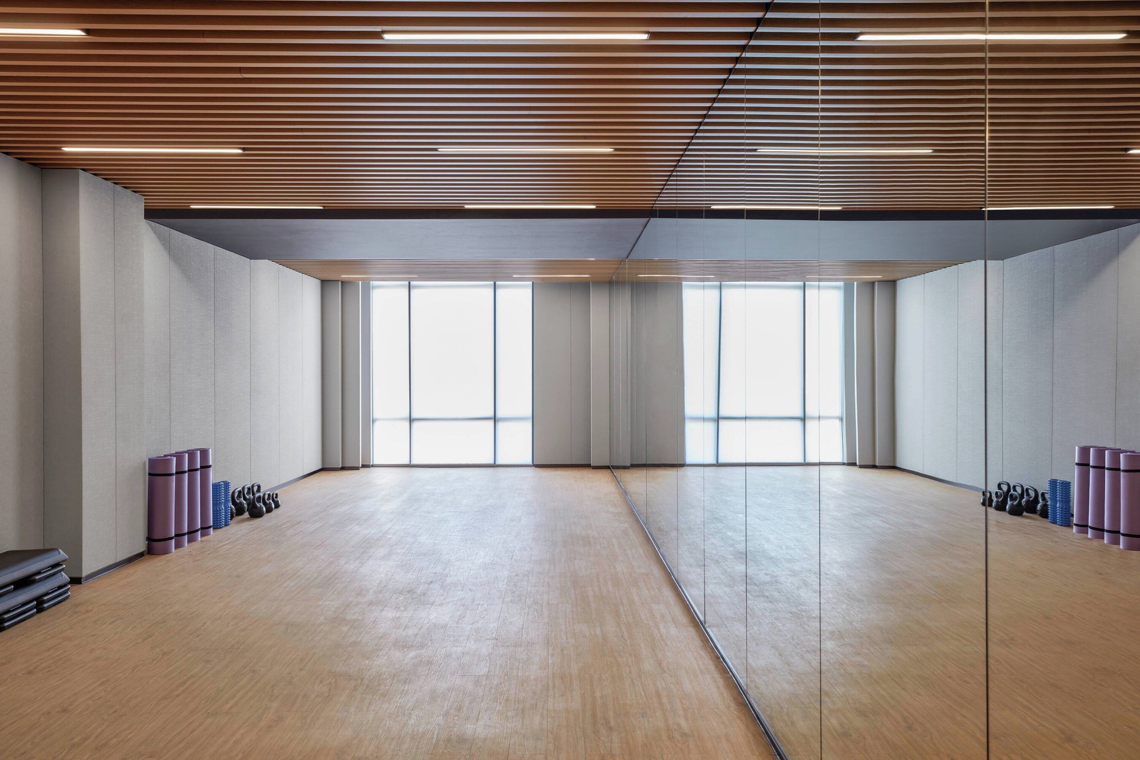 A spacious room with a wooden ceiling, large windows, and exercise equipment.