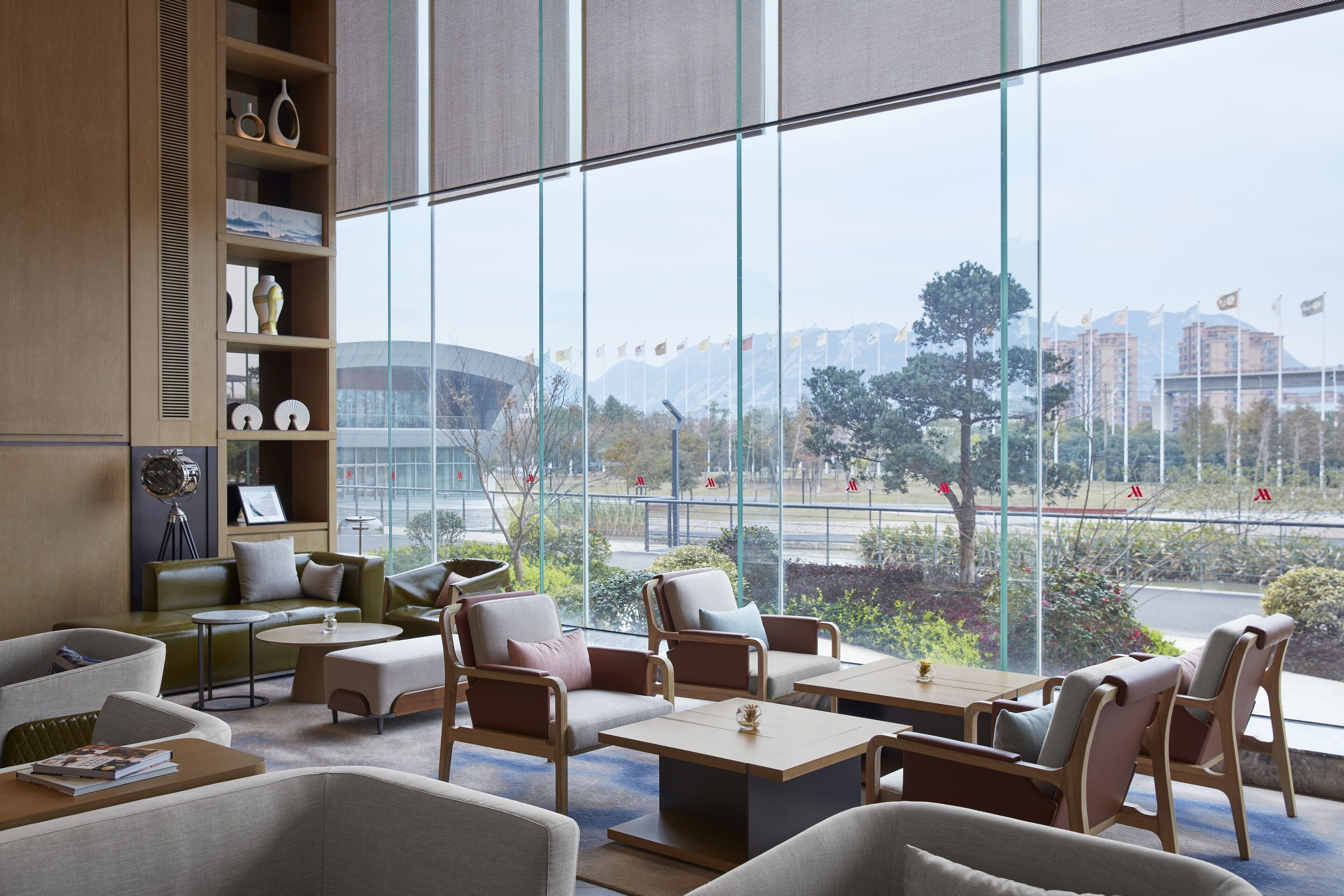 Ein moderner Lounge-Bereich mit großen Fenstern, bequemen Sitzgelegenheiten und Blick auf die Stadtlandschaft.