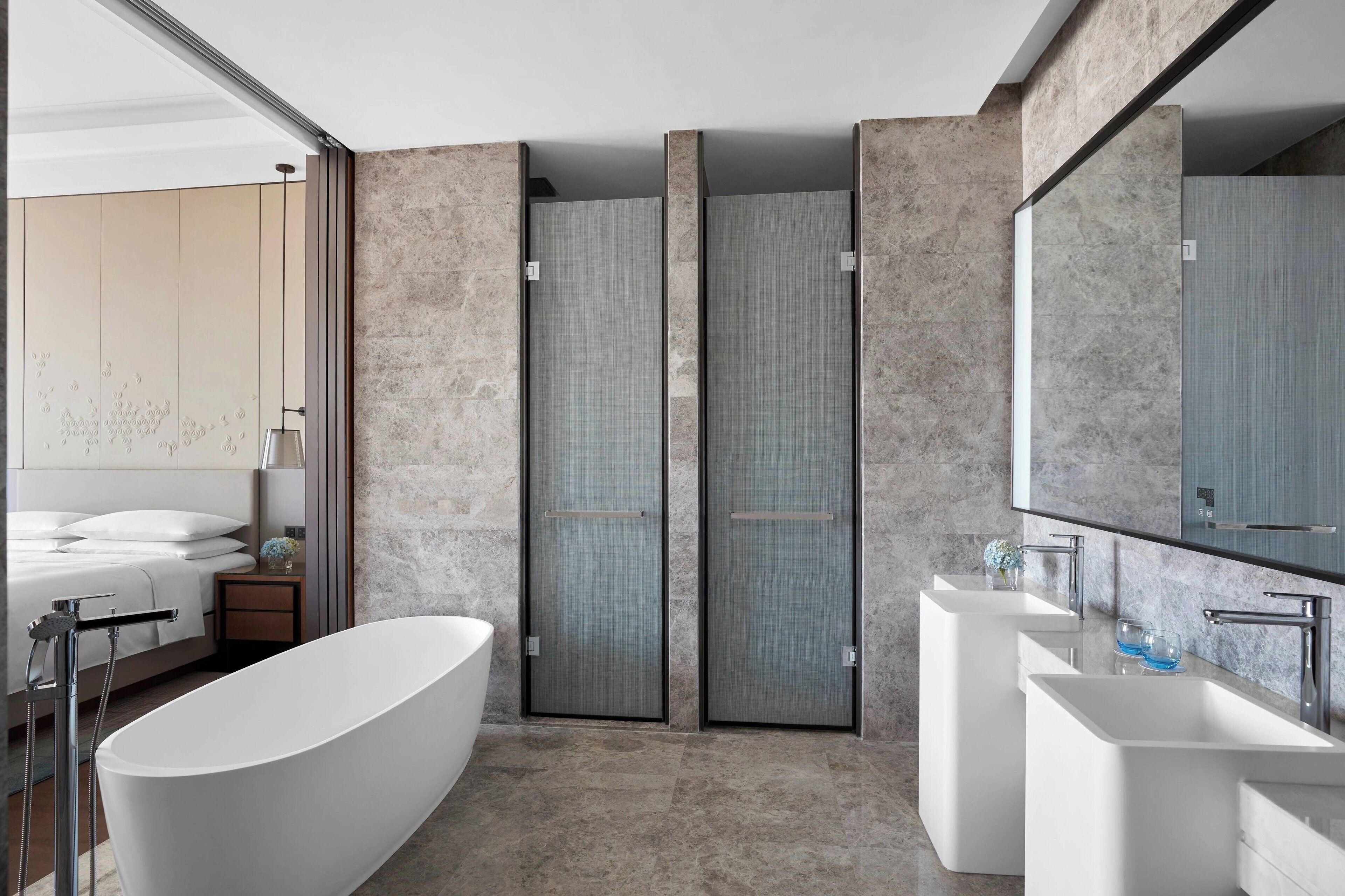 Un baño moderno con una bañera independiente, un espejo grande y un lavabo doble.