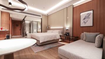 Una habitación de hotel moderna con una cama, un sofá, un escritorio y un espejo grande.