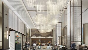 Eine moderne Lobby mit einer zentralen Sitzecke, einem Empfangsbereich und einer gemusterten Decke.