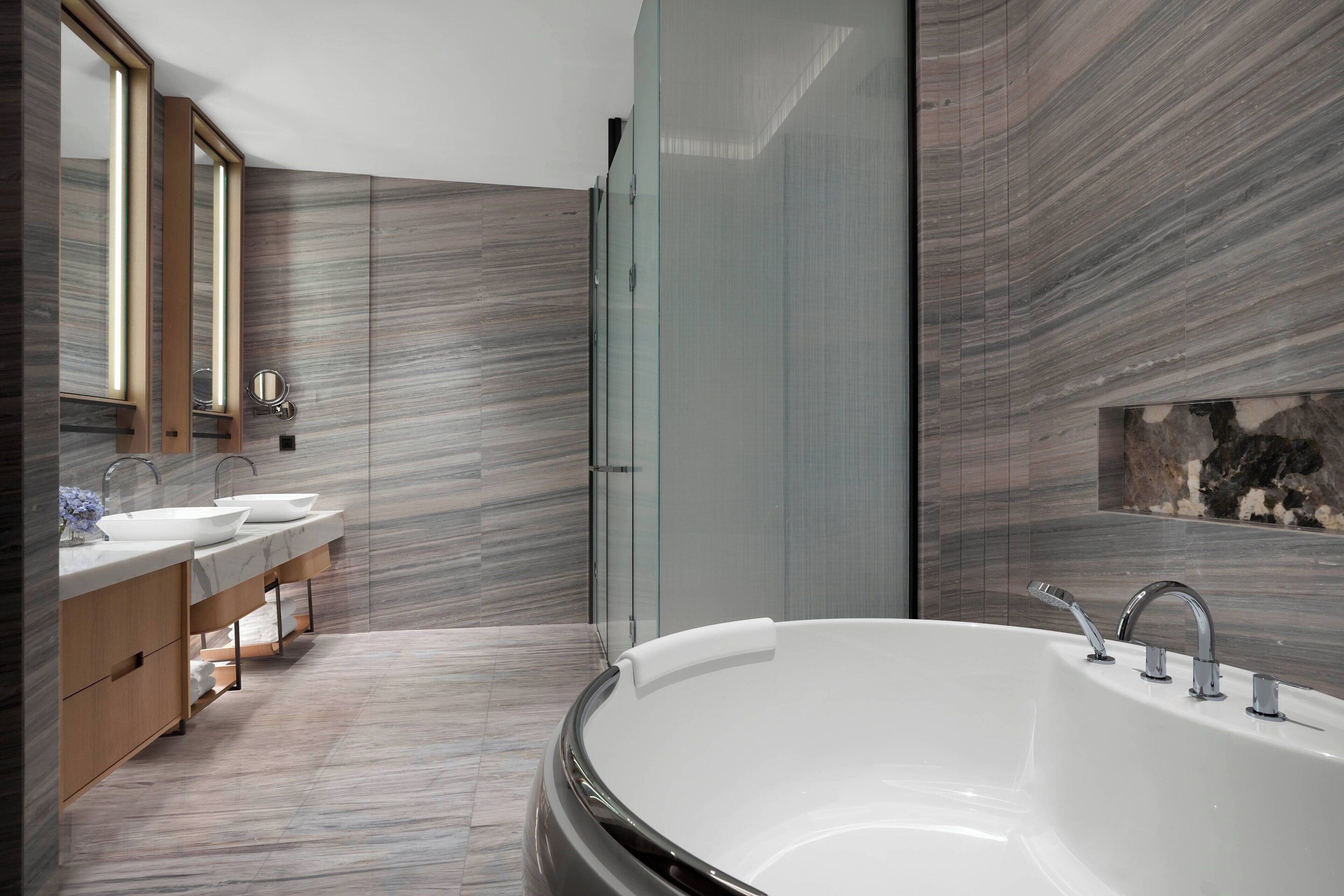 A modern bathroom with a freestanding bathtub, two sinks, and a large mirror.