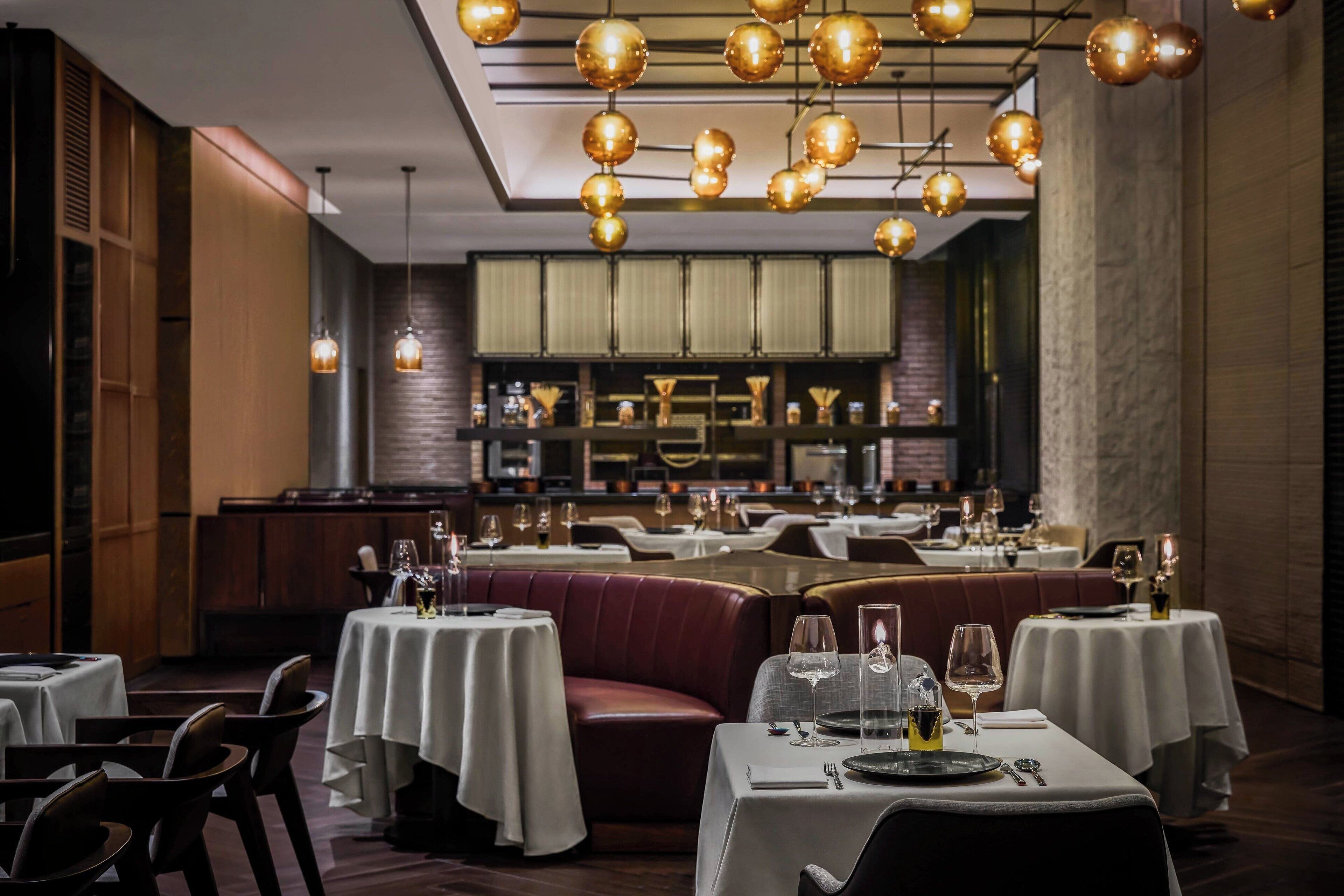 A restaurant with multiple tables and booths, warm lighting, and a modern interior design.