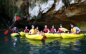Um grupo de pessoas fazendo caiaque em uma caverna com paredes rochosas e água.