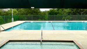 Ein rechteckiger Pool mit Sprungbrett im Vordergrund und einem überdachten Bereich.