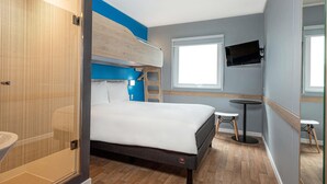 A modern hotel room with a bunk bed, a small desk, a TV, and a shower area. - ibis Budget Lima Miraflores (Lima)