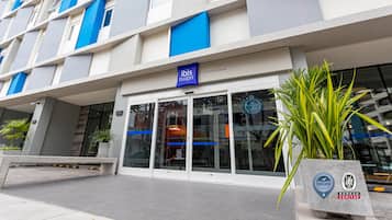 Un bâtiment moderne à la façade bleue et blanche, doté d’une entrée en verre et d’une enseigne indiquant « ibis Budget ».
