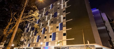 A modern hotel with a multi-story structure, large windows, and a visible entrance.