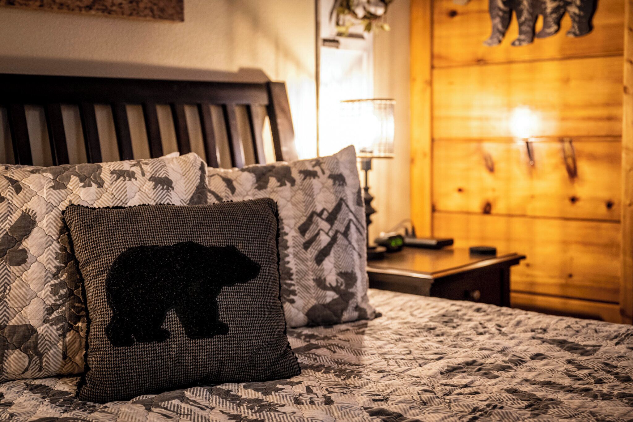 Un lit avec une literie à motifs et un oreiller orné d’un dessin d’ours.