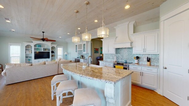 A spacious kitchen with a large island, white cabinetry, and a ceiling fan. - EnJoy the View: 4  BR, 3  BA House in Crystal Beach, Sleeps 13 (Bolivar Peninsula)
