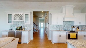 A kitchen with white cabinetry, a central island, and a stainless steel refrigerator. - EnJoy the View: 4  BR, 3  BA House in Crystal Beach, Sleeps 13 (Bolivar Peninsula)