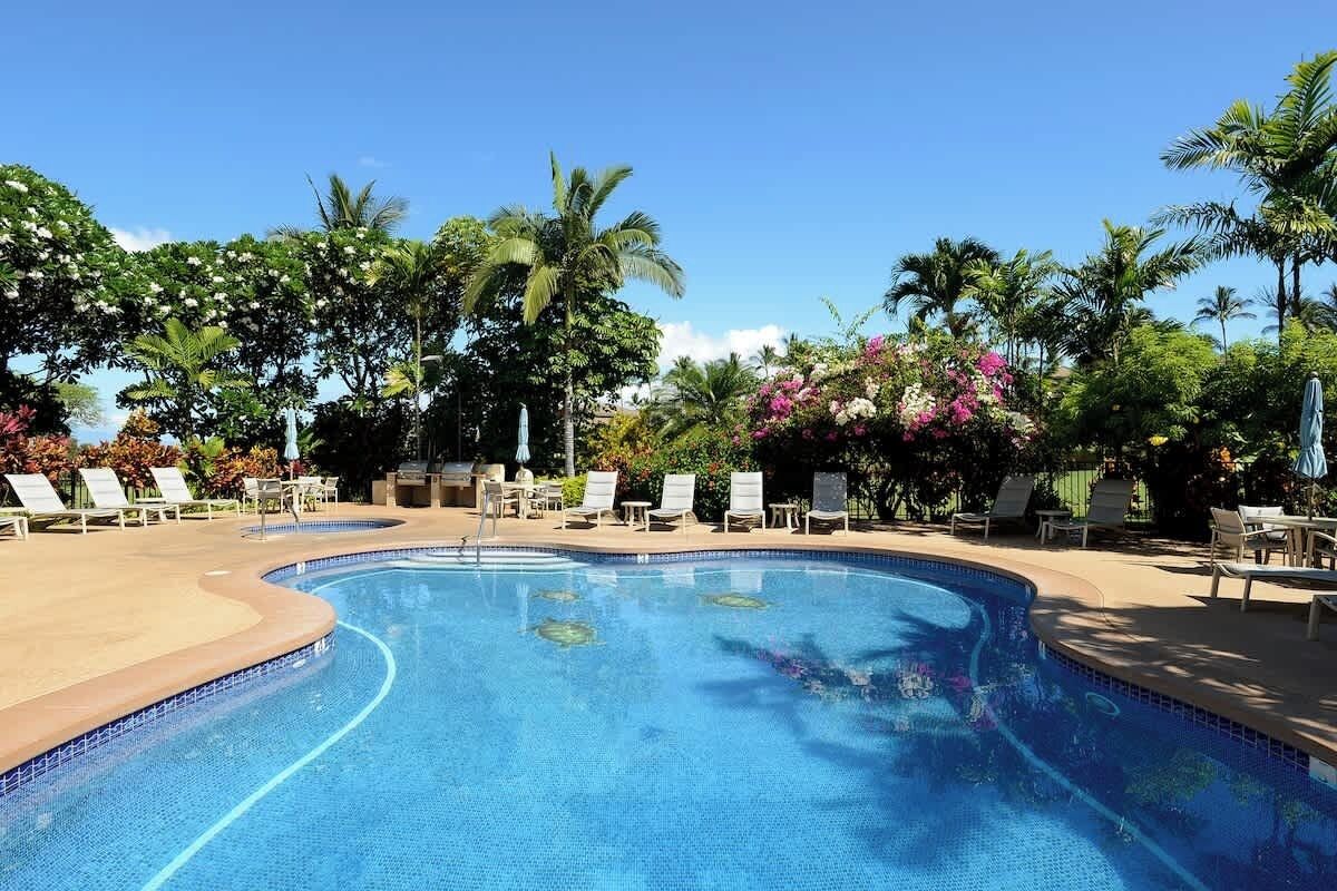 A swimming pool with lounge chairs and palm trees.