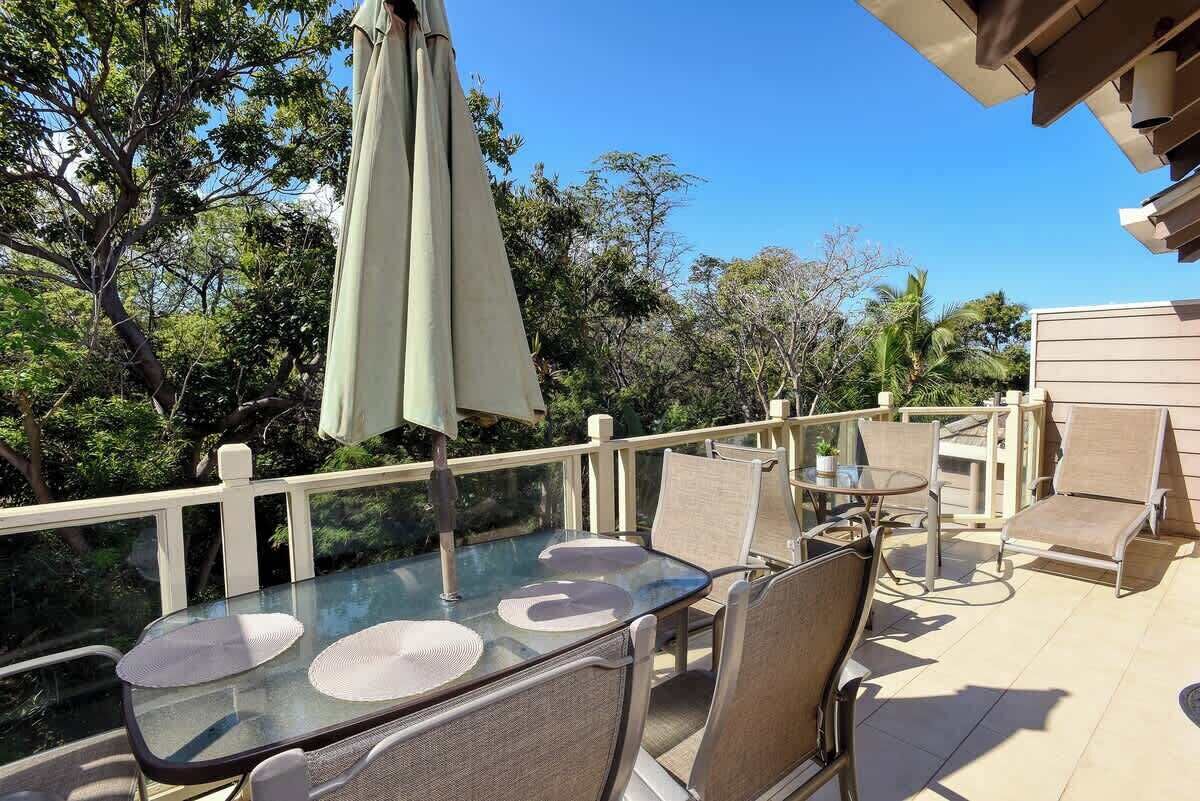 Mesa de vidrio con cuatro sillas y un paraguas en un patio exterior.