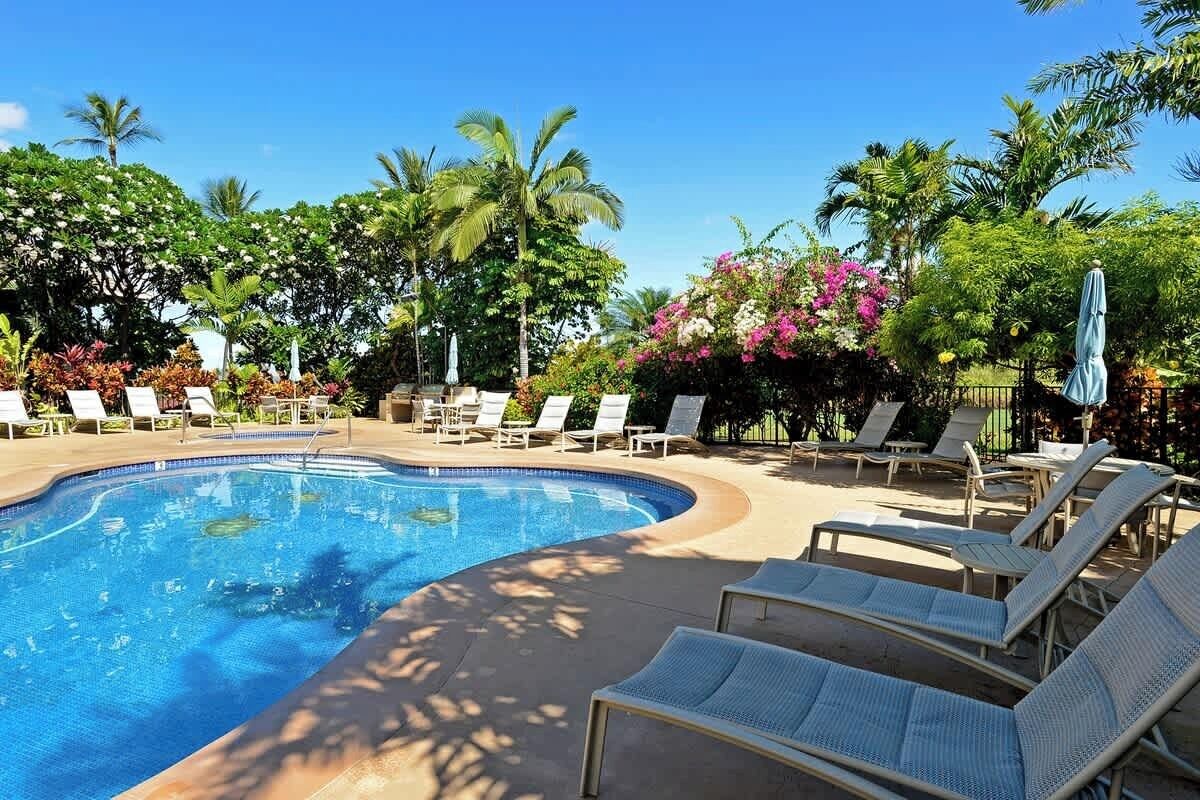 A swimming pool with lounge chairs and tropical plants.