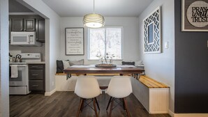 Een moderne keuken met een centraal eiland, witte barstoelen en een hangende lamp.