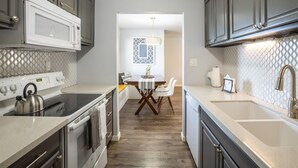 Een moderne keuken met roestvrijstalen apparatuur, een eetgedeelte met een tafel en stoelen, en een achterwand met een patroon.