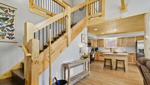 A spacious kitchen with wooden flooring, a central island with stools, and a built-in oven. - New Log Cabin in the Valley, Elk Experience, Year Round Access (Maggie Valley)