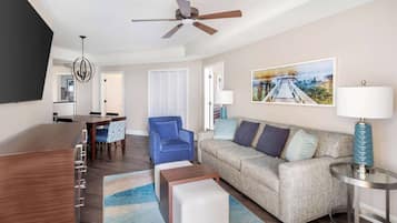 A modern living room with a sofa, ottoman, coffee table, and a dining area with chairs and a table.