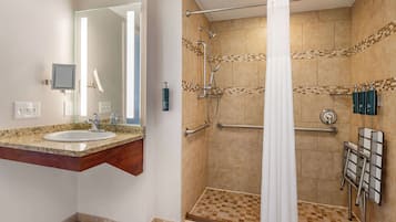 Un baño con lavabo, espejo, ducha con puerta de vidrio y barra para toallas.