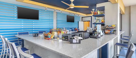 Een bar met een toog, zitplaatsen en een plafondventilator.
