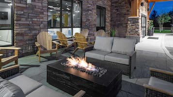An outdoor seating area with a fire pit, wicker furniture, and a stone wall.