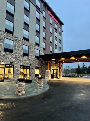 A hotel with a stone facade, multiple windows, and a well-lit entrance.