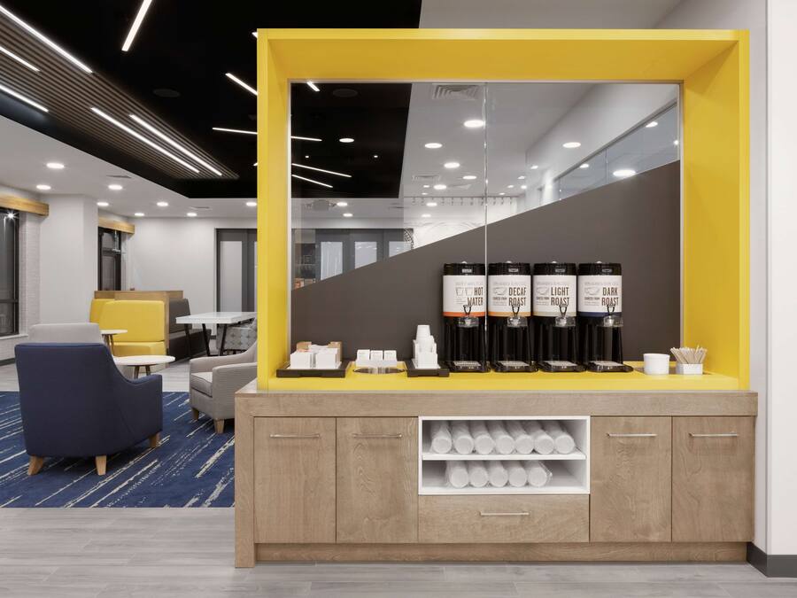 A modern reception area with a yellow counter, seating, and a coffee station.