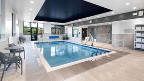 An indoor swimming pool with a blue border, surrounded by seating areas and a reception desk. - Hampton Inn Verona at Turning Stone (Verona)