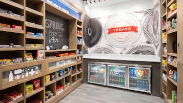 A snack and beverage display area with shelves stocked with various snacks and drinks, and a wall with a 'Spring is the Air' sign and a 'Treats' sign.