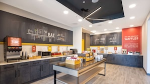 A modern cafe with a chalkboard menu, espresso machine, and waffle station. - Hampton Inn Verona at Turning Stone (Verona)