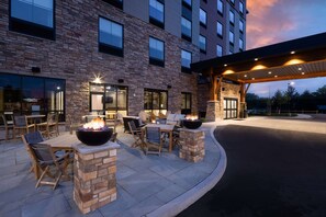 An outdoor patio with stone walls, wooden furniture, and a fire feature. - Hampton Inn Verona at Turning Stone (Verona)