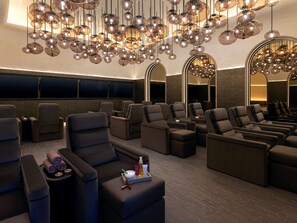 A cinema with reclining seats, a tray table, and a tray with a bottle, bowl, and spoon. - Crockfords Las Vegas, LXR Hotels & Resorts at Resorts World (Las Vegas)
