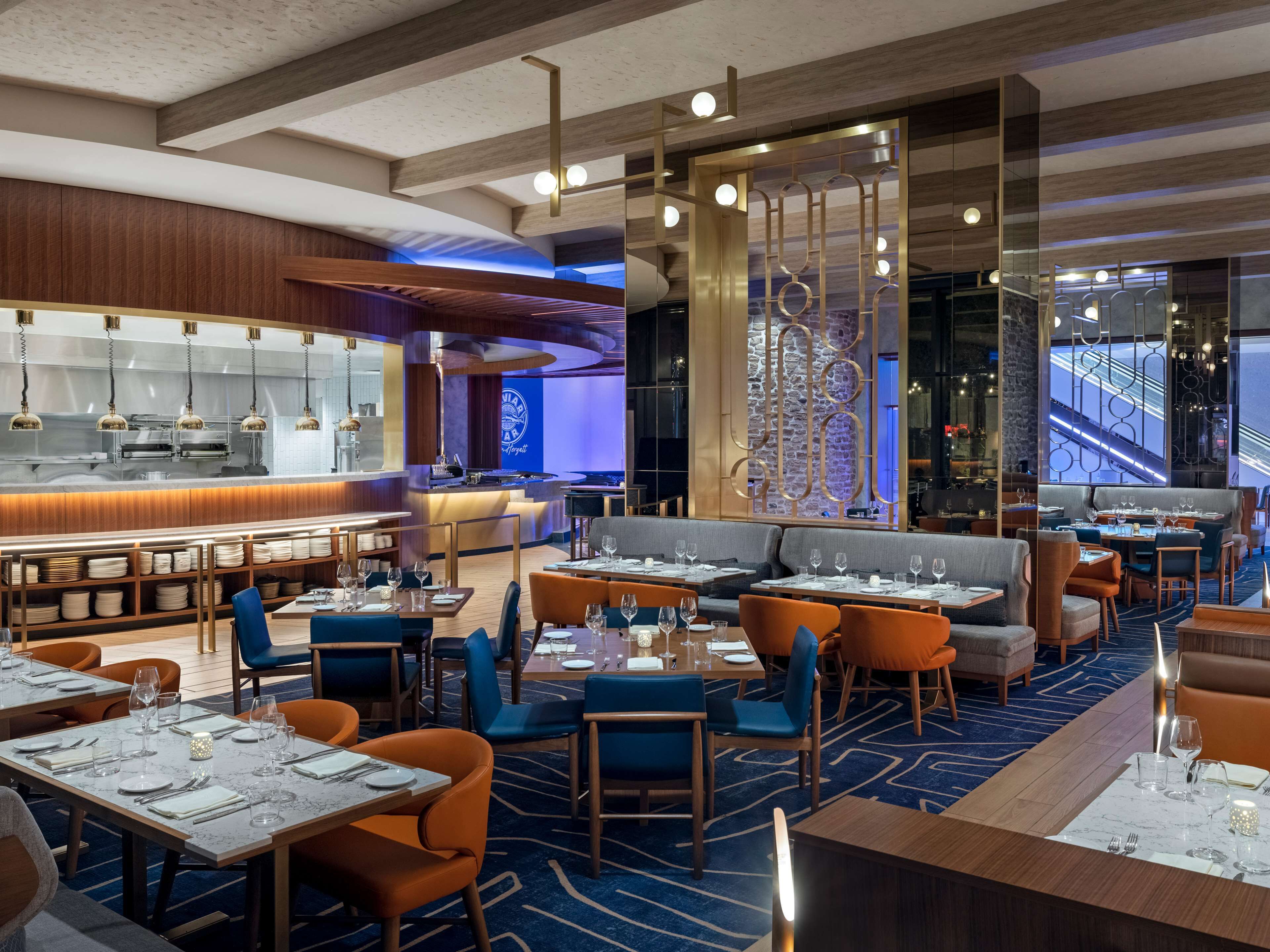 Un restaurante moderno con barra, distribución de mesas y una pared decorativa con un diseño geométrico.