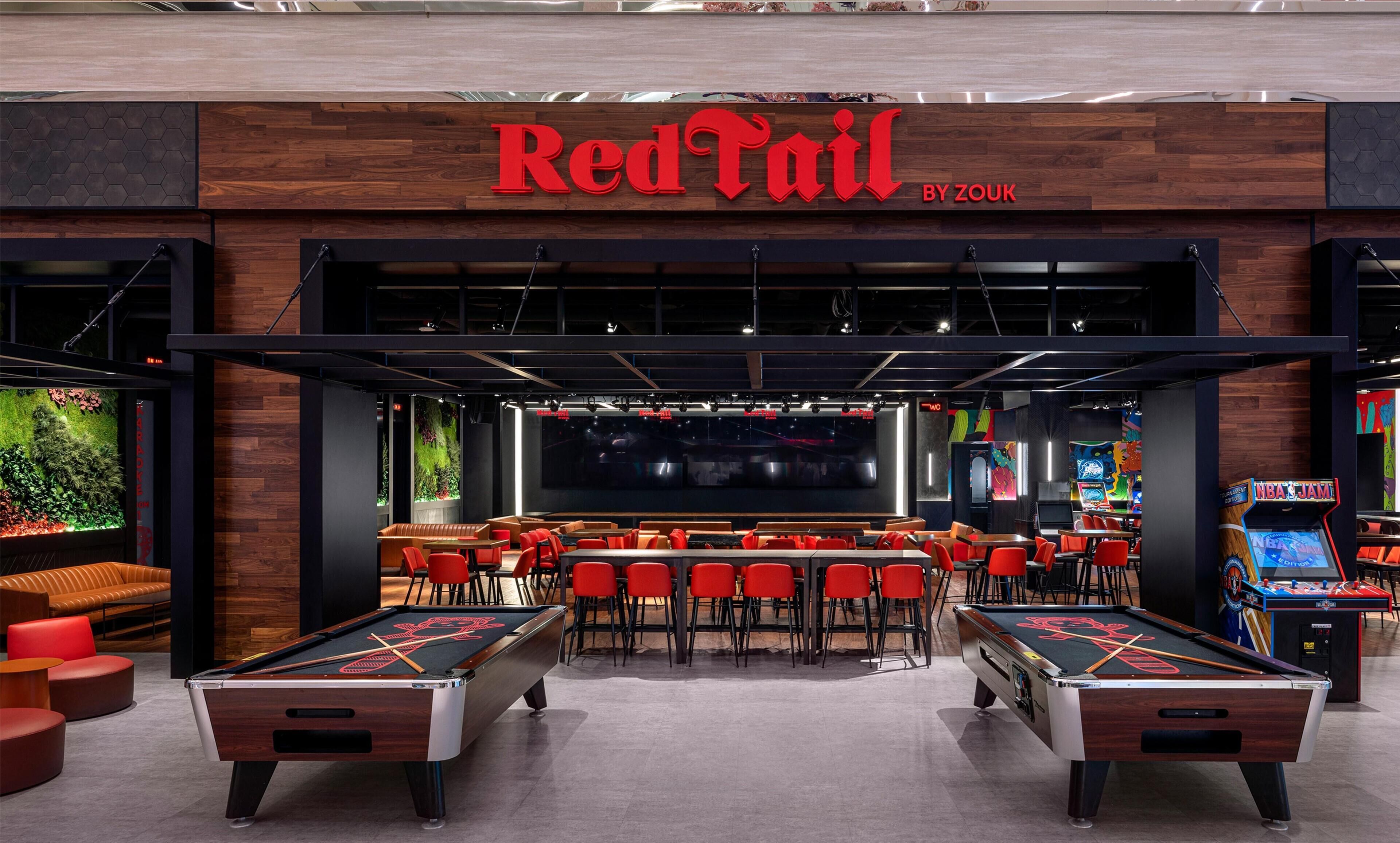 Bar Rojo con mesas de billar, asientos y juegos de arcade.