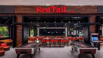 Bar Rojo con mesas de billar, asientos y juegos de arcade.