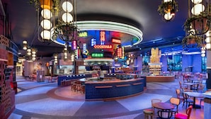 Un espace bar moderne, agrémenté d’enseignes au néon, de sièges et d’un comptoir circulaire.